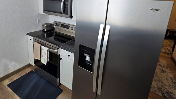 Eine kompakte Küche mit Edelstahlkühlschrank, Mikrowelle, Toaster und Backofen.
