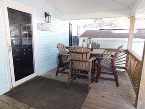 A covered porch with a wooden table and chairs, a sign reading 'Welcome to the Beach,' and a door leading to a garage. - 1865 All new furnishings sleeps 10 separate loft for children (Myrtle Beach)