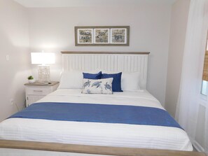 A bedroom with a bed, a nightstand, a lamp, and three framed pictures on the wall. - 1865 All new furnishings sleeps 10 separate loft for children (Myrtle Beach)