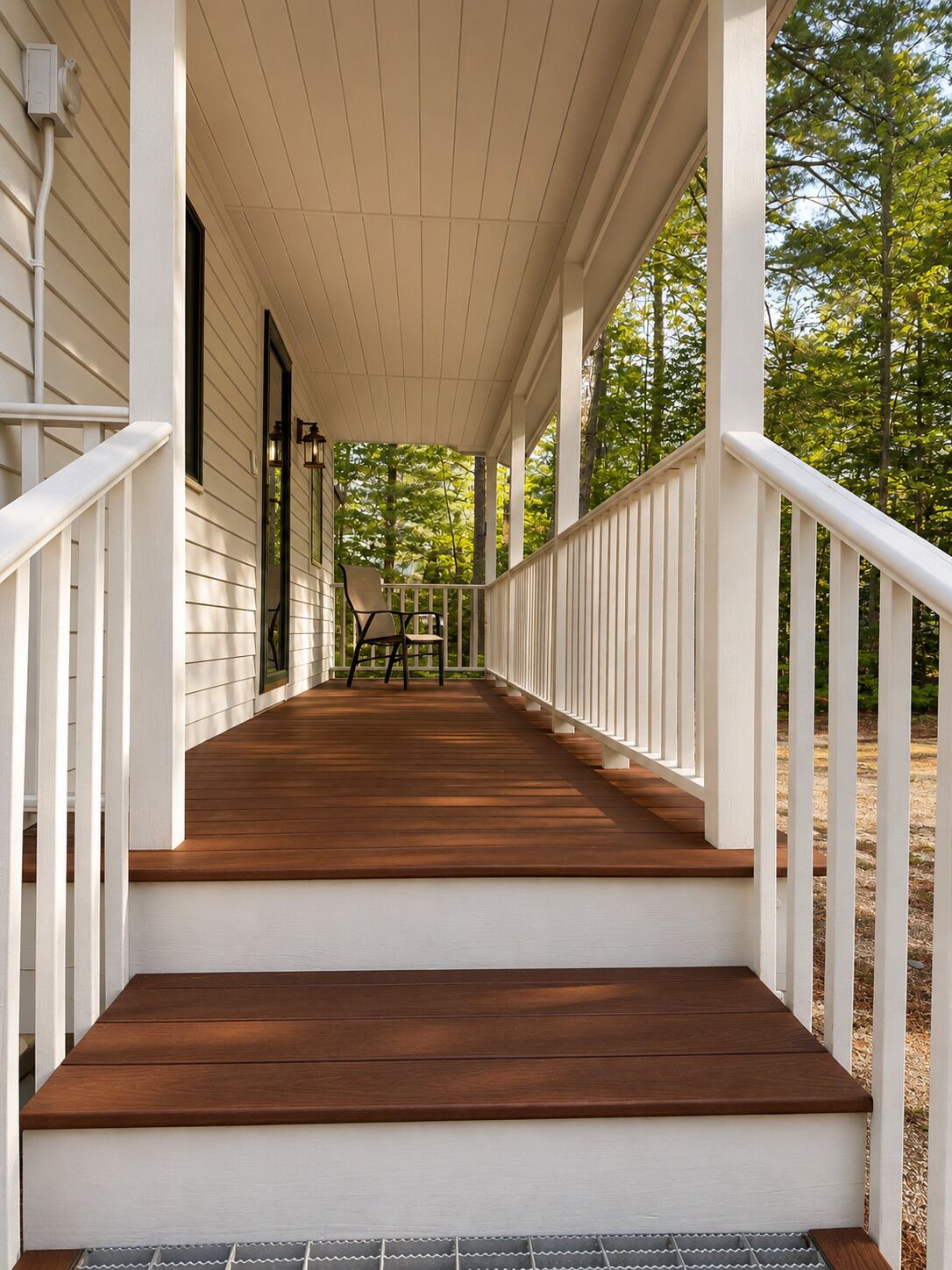 A wooden porch with white railings, a bench, and a door leading to the house.