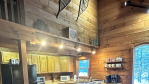 A modern kitchen with wooden cabinets, a central island with stools, a refrigerator, a microwave, and a coffee machine. - Enjoy an all seasons retreat, perfect for relaxing getaways in Tamworth NH (Tamworth)