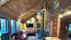 A cozy cabin interior with a wooden ceiling, a large sofa, a TV, and a bar area. - Enjoy an all seasons retreat, perfect for relaxing getaways in Tamworth NH (Tamworth)