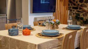 A dining table set with blue and orange dishes, glasses, and a vase with flowers. - Complete 4 Bedroom House near Termas de Bande and Lobios - Villa Limia (Chaos)