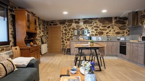 A modern kitchen with stone walls, wooden cabinets, and a dining area with a table and chairs. - Complete 4 Bedroom House near Termas de Bande and Lobios - Villa Limia (Chaos)