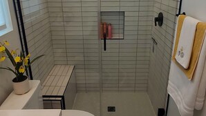 Ett modernt badrum med en dusch som är avskärmad med glasväggar, en toalett och ett handfat.