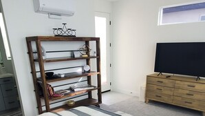 Ett sovrum med en säng, en bokhylla i trä, en tv och ett fönster.