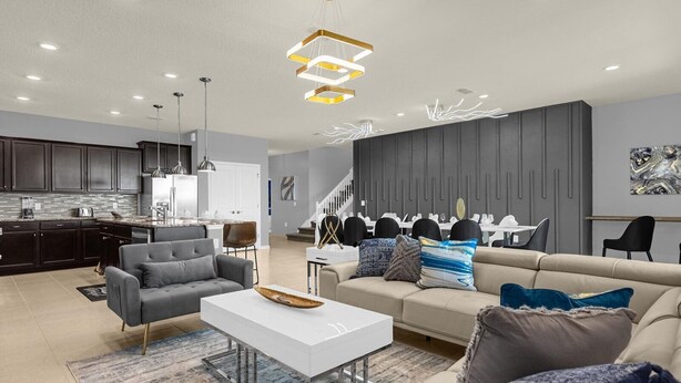 Un salon moderne avec un canapé gris, une table basse blanche et un coin repas comprenant une table blanche et des chaises noires.