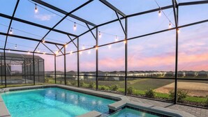 Une piscine dotée d’une enceinte en verre, entourée d’une structure métallique et illuminée de guirlandes lumineuses.