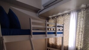 Ein Schlafzimmer mit Etagenbett, Fenster, Vorhängen und einer Klimaanlage.
