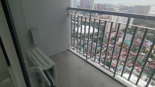 Ein Balkon mit Metallgeländer, einem kleinen Tisch und einem Stuhl.