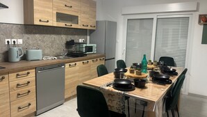 Cocina moderna con armarios de madera, lavavajillas, microondas y una mesa de comedor con sillas.