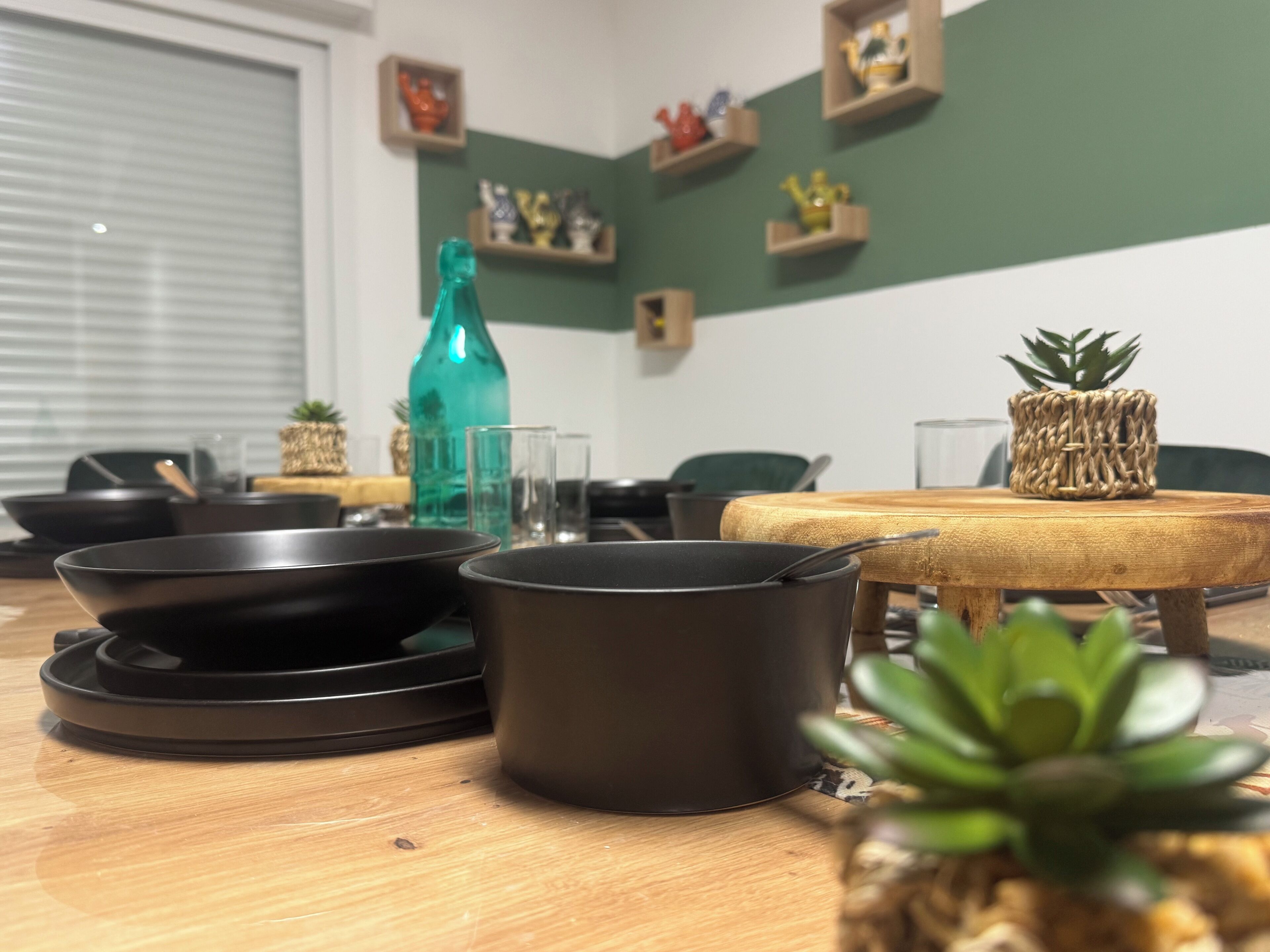 A dining table with black cookware, a green bottle, and a small plant.