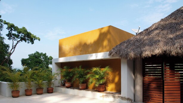 A modern building with a flat roof, potted plants, and a stone-tiled patio. - Spacious 2 Bed, 2 Bath Apartments - 10 Minute Walk to Beach, Dining & Shopping (La Manzanilla del mar municipio de la Huerta)