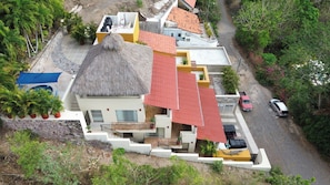 A multi-story building with a thatched roof, a swimming pool, and a paved driveway.
