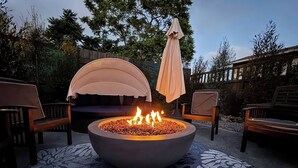 A circular fire pit with flames, surrounded by outdoor furniture and a patterned rug. - Overlook Heights Retreat in beautiful San Diego by USD (San Diego)