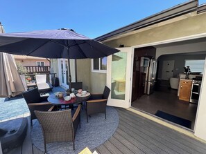 Un patio al aire libre con una mesa, sillas y una sombrilla grande.
