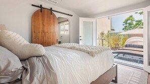 A bedroom with a bed, a wooden door, and a view of an outdoor seating area. - Overlook Heights Retreat in beautiful San Diego by USD (San Diego)
