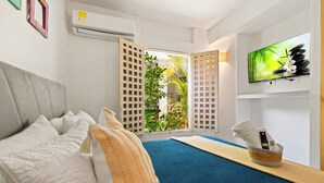 Una camera d'hotel con un letto, una TV fissata al muro e una finestra che si affaccia sul verde.