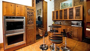 A kitchen with wooden cabinets, stainless steel appliances, and a dining area with a round table and chairs. - View Carrie de Maison - 1 block to French Quarter (New Orleans)