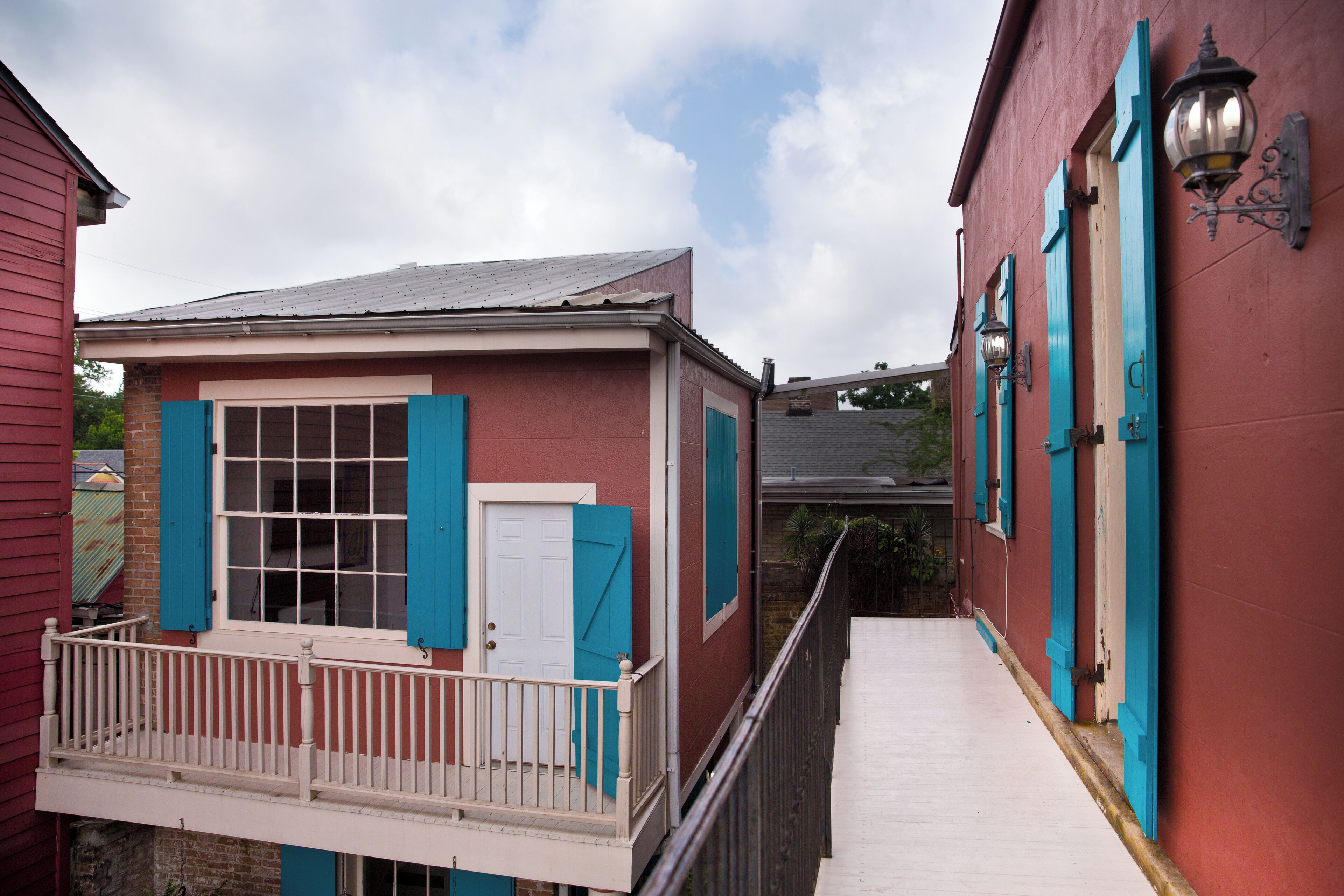 A narrow alleyway with a red building on the right and a red building on the left.