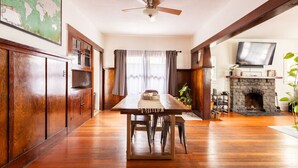 A spacious living room with a wooden floor, a dining table, a fireplace, and a television. - Craftsman 2 blocks from Russian River Brewery! (Santa Rosa)