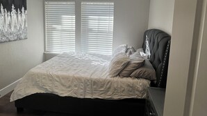 A bedroom with a bed, a ceiling fan, and two windows with blinds.