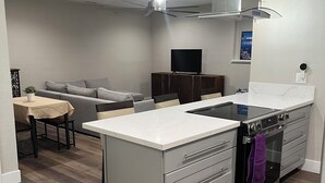 A modern kitchen with a central island, built-in oven, and a dining area with a sofa and table.