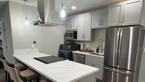 A modern kitchen with a central island, stainless steel appliances, and a bar seating area.
