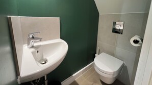Une salle de bain avec un lavabo blanc, des toilettes et un mur vert.