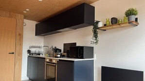 Une cuisine moderne avec un plan de travail noir, des appareils en acier inoxydable et une porte en bois.