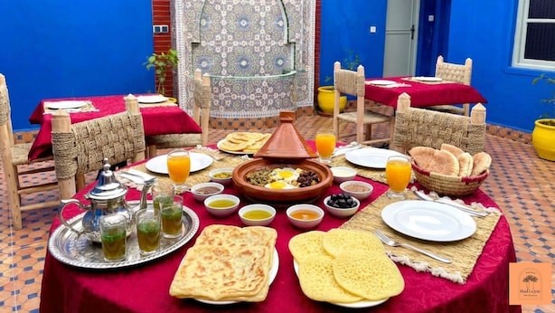 Un montaje tradicional marroquí para la cena, con una mesa dispuesta para dos personas, que incluye un tajine, panes planos y diferentes platos.
