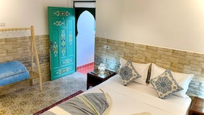 Un dormitorio con cama, una silla de madera, una mesita de noche y una puerta decorativa.