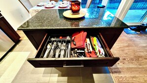 Een keuken met een lade-organizer met keukengerei en een kaars op het aanrecht.