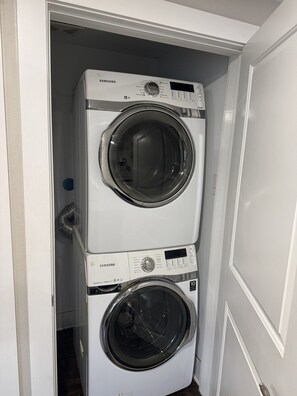 Eine übereinander gestellte Waschmaschine und ein Trockner in einem Waschraum.