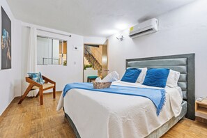 Ein Schlafzimmer mit einem Bett, einem Sessel, einem Fenster und einer Klimaanlage.
