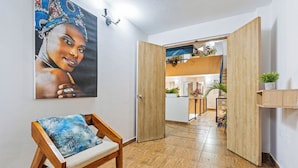 Una habitación con un banco de madera, un cuadro en la pared y una puerta abierta que da a otra estancia con plantas.