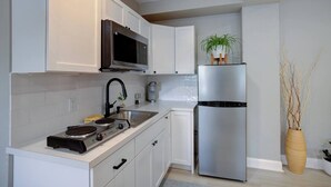 Une cuisine moderne avec des meubles blancs, un réfrigérateur en acier inoxydable, un four à micro-ondes et une cuisinière à gaz.