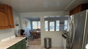 A kitchen with green cabinets, a stainless steel refrigerator, and a tiled floor.
