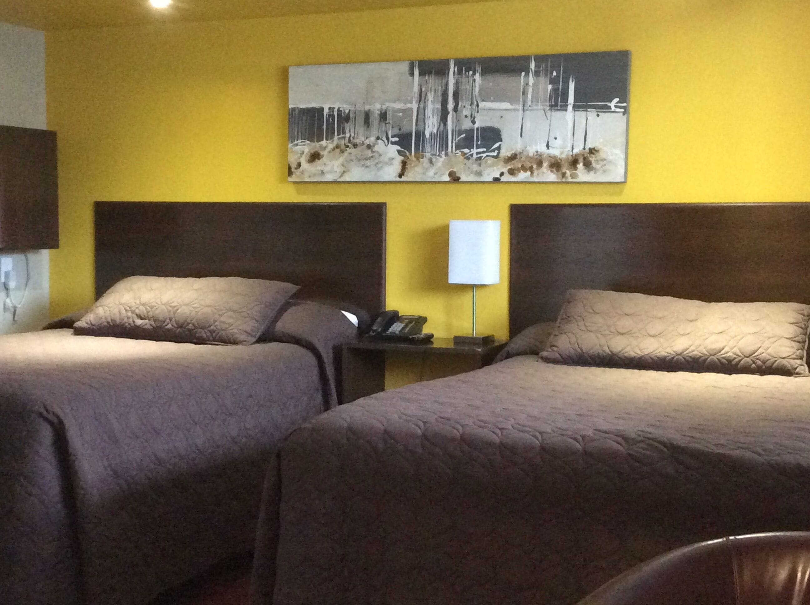 Ein Hotelzimmer mit zwei Betten, einem Nachttisch mit Lampe und einem Bild an der Wand.