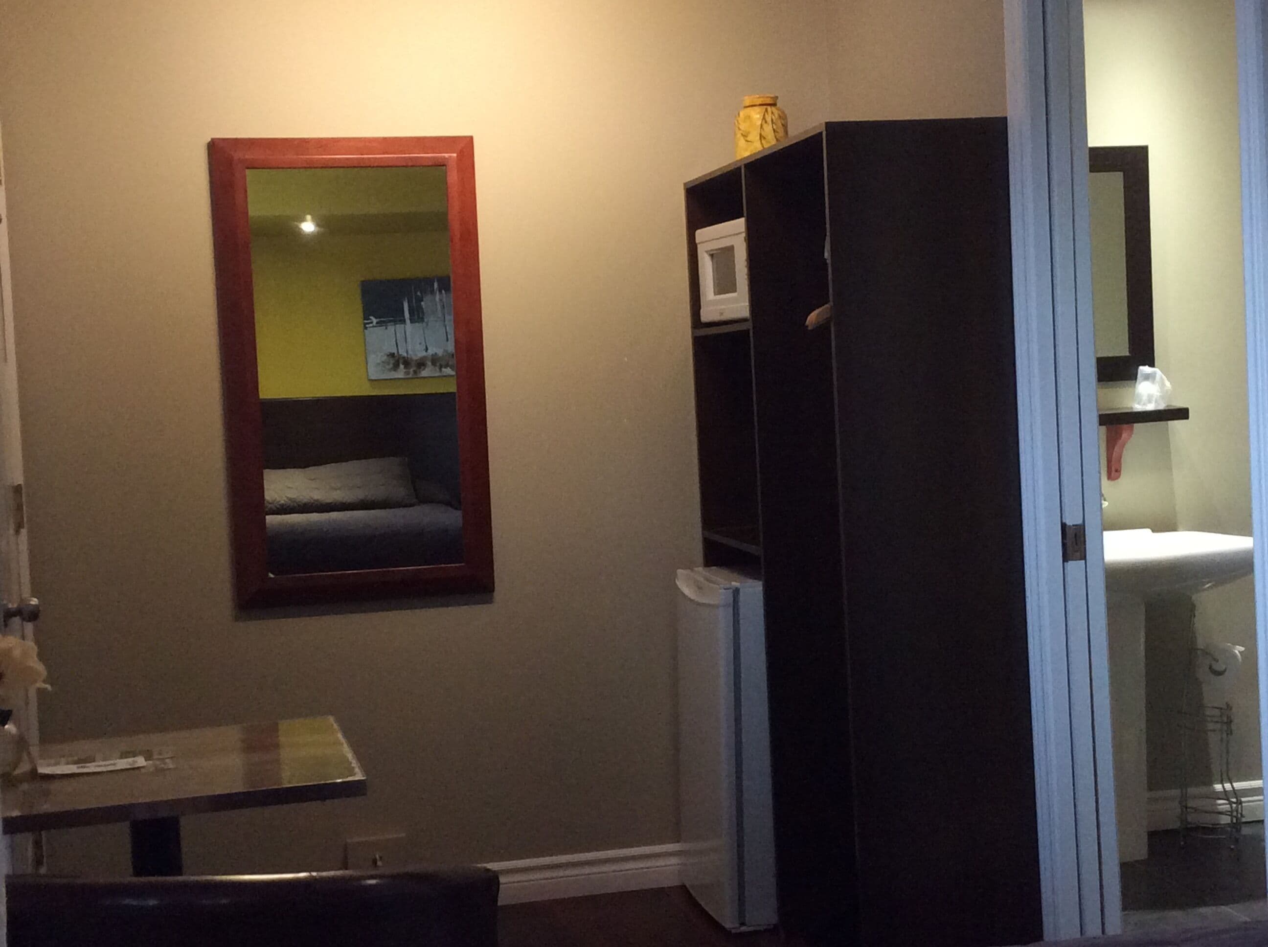 A room with a bed, a small table, a mirror, and a wardrobe.