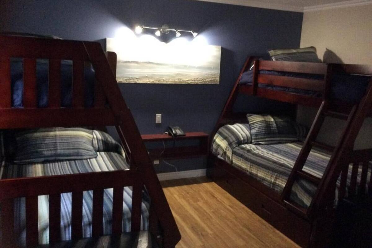 A room with bunk beds, a desk, and a wall-mounted lamp.