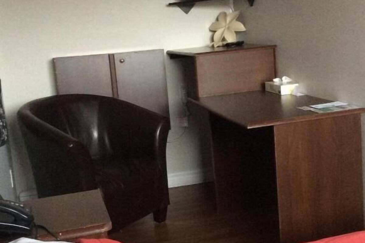 A hotel room with a bed, a desk, a chair, a television mounted on the wall, and a small decorative item on the desk.