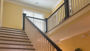 A staircase with wooden steps and white railings, leading to a landing with a window and a wall-mounted wreath. - Lakefront Lake Oconee Retreat ~ 5BR/4.5BA ~ MASTERS WEEK ONLY (Eatonton)