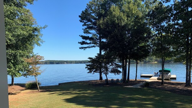 A lakeside view with a dock, chairs, and a boat. - Lakefront Lake Oconee Retreat ~ 5BR/4.5BA ~ MASTERS WEEK ONLY (Eatonton)