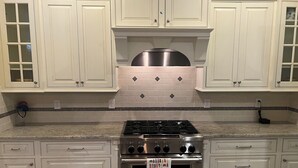 A kitchen with white cabinetry, a stainless steel stove, and a backsplash with black and white tiles. - Lakefront Lake Oconee Retreat ~ 5BR/4.5BA ~ MASTERS WEEK ONLY (Eatonton)