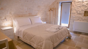 Une chambre à coucher avec un lit, une table de chevet, une chaise et une fenêtre.