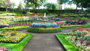 A formal garden with a central fountain, manicured lawns, and flower beds. - Charming 19th-Century Georgian Townhouse – Heart of Shrewsbury (Shrewsbury)