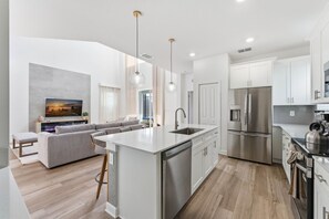 A modern kitchen with a central island, stainless steel appliances, and a dining area with a sofa and coffee table.