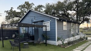 A small house with a covered patio area, outdoor seating, and a well-maintained lawn. - Amazing 2-bedroom house in beautiful Houston with AC (Houston)