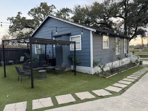 A small house with a covered patio area, outdoor seating, and a well-maintained lawn. - Amazing 2-bedroom house in beautiful Houston with AC (Houston)